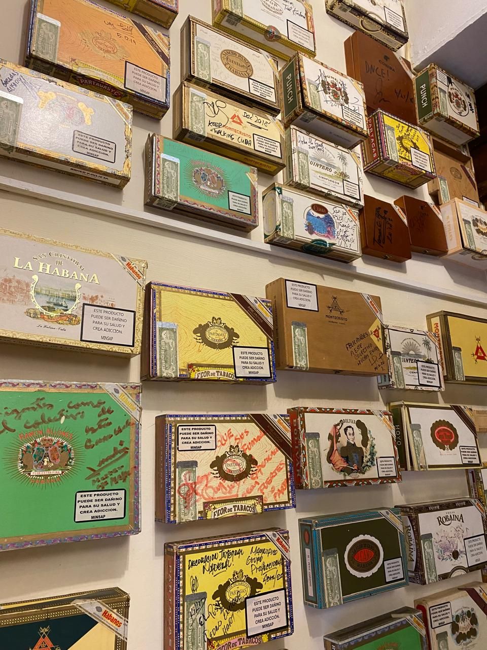 Pared cubierta de cajas de habanos firmadas por visitantes