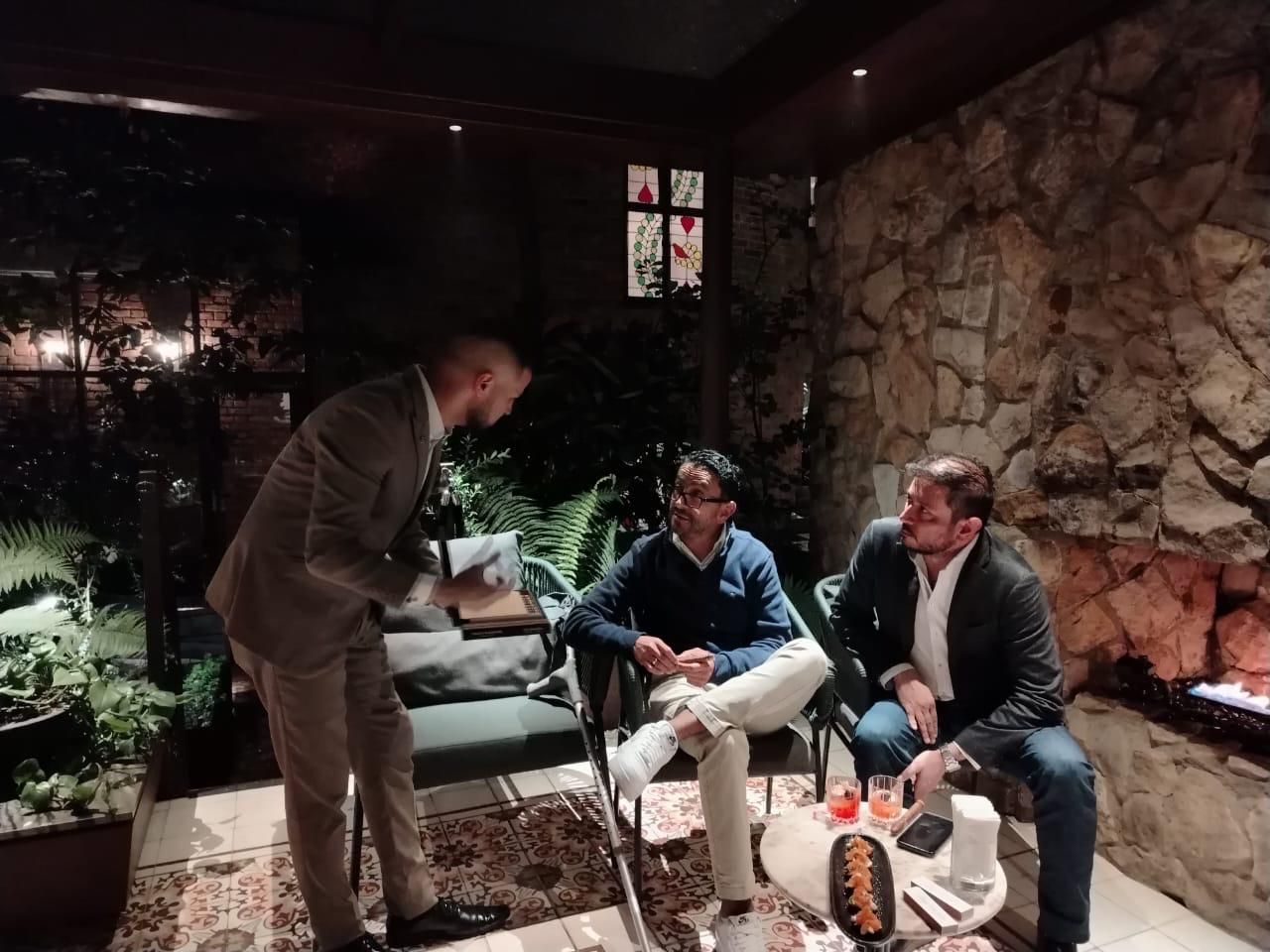 Alejandro presenta una selección de habanos a dos invitados en una terraza