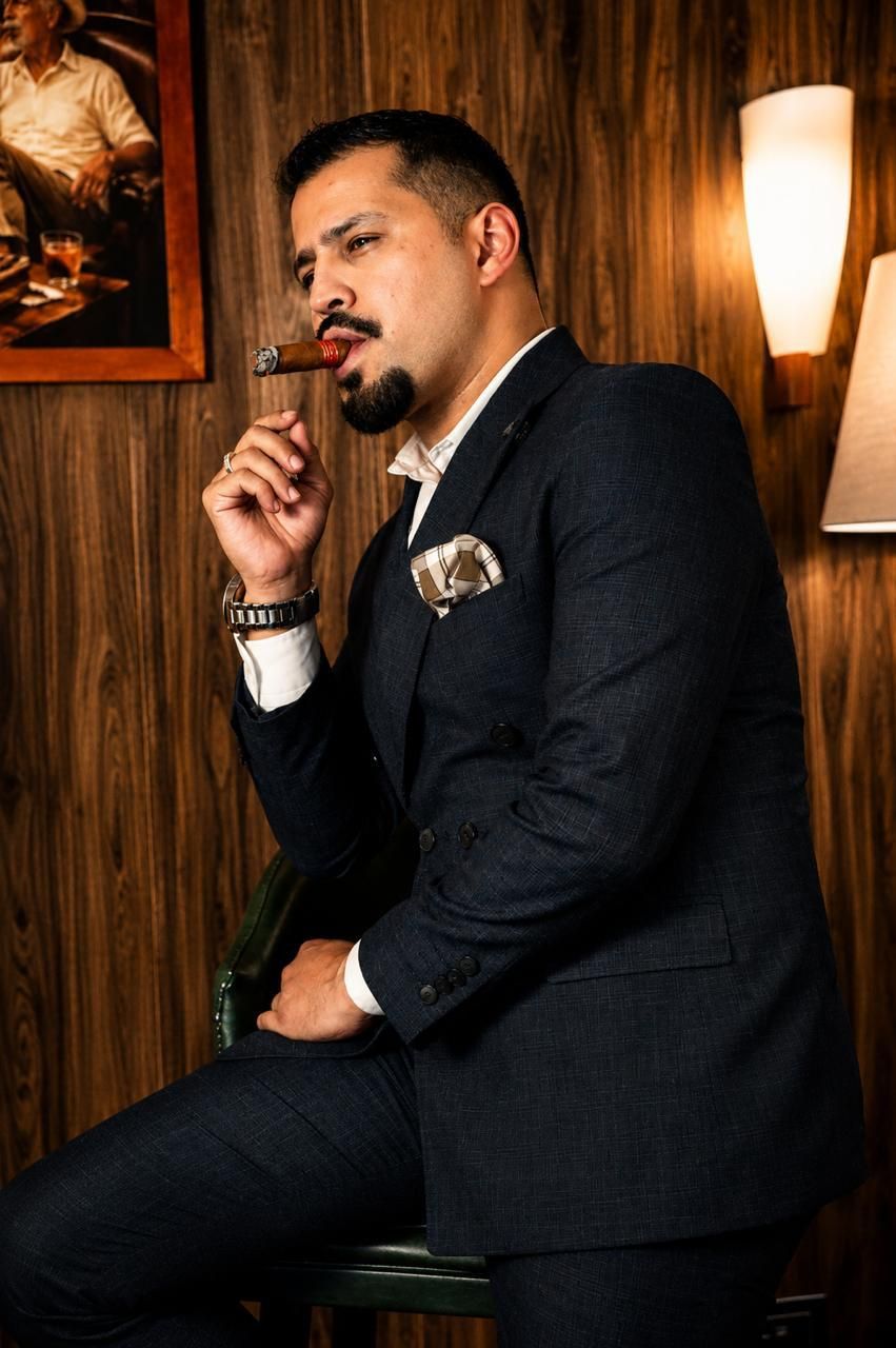 Alejandro fumando un habano, sentado en un salón con paredes de madera